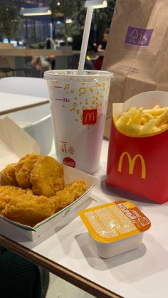 chicken nuggets and fries are sitting on a table next to a cup of mcdonald's