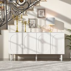 a white cabinet sitting in front of a stair case next to a potted plant