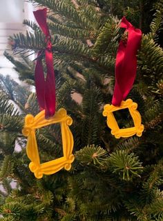 two christmas ornaments hanging from a tree with red and yellow ribbons on it's sides