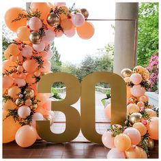 the balloon arch is decorated with gold and pink balloons that spell out the number thirty