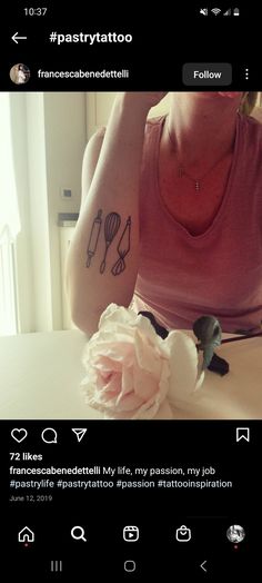 a woman sitting at a table with a flower in front of her and tattoos on her arm