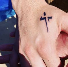 a person's hand with a cross tattoo on it