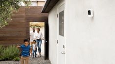 a young boy standing in front of a door with his family walking behind him outside