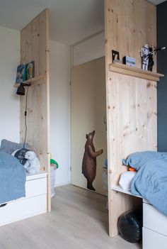 a bear is standing in the corner of a room next to a bed and shelves