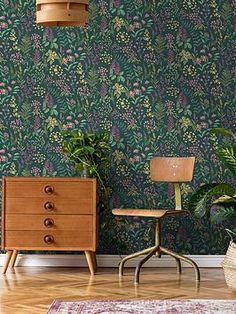 a living room with green wallpaper and wooden furniture in front of a plant filled wall