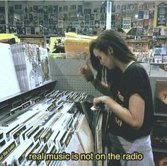 a woman standing in front of a rack of musical instruments with the caption real music is not on the radio