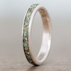 a wedding ring with green and white speckles