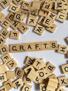 wooden scrabbles spelling the word craft with letters scattered around them on a white surface