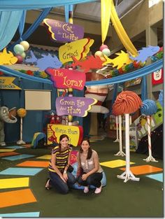 two people sitting on the ground in front of a room with decorations and signs hanging from it