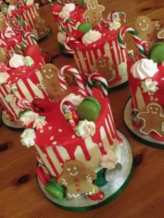 several decorated christmas cakes sitting on top of a wooden table with candy canes and candies