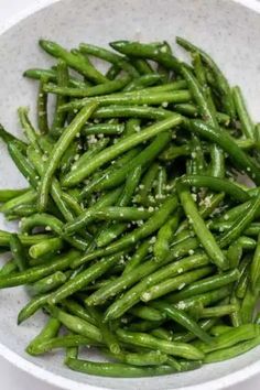 a white bowl filled with green beans on top of a table