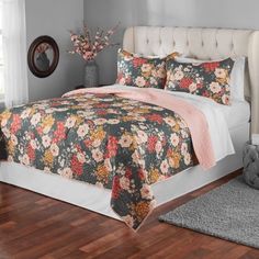 a bed with flowers on it in a bedroom next to a window and rugs