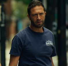 a man in a blue shirt walking down the street