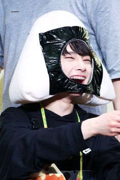 a boy with a pillow on his head and another person holding something in front of him