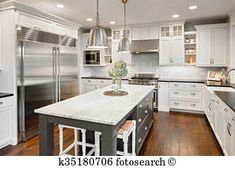 a large kitchen with white cabinets and stainless steel appliances, along with hardwood flooring