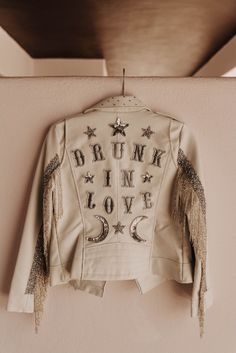 a white jacket with stars and the words drink love on it hanging from a hook