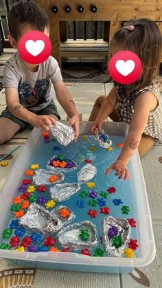 two children are playing with plastic beads and paper hearts