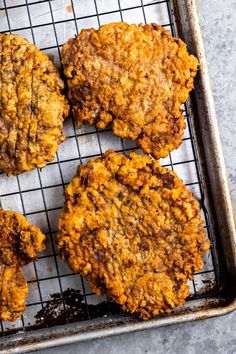 four hamburger patties on a cooling rack with raisins in the foreground