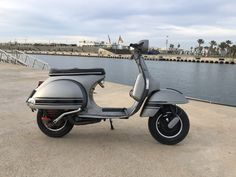 a motor scooter parked next to a body of water