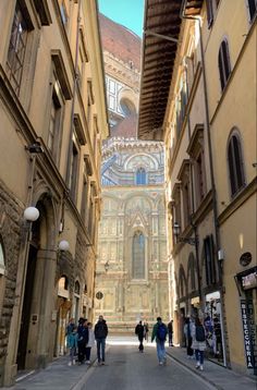 people are walking down an alley way between two buildings with arches and arched doorways