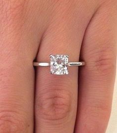 a woman's hand with a ring on her finger and a diamond in the middle