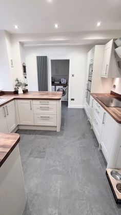 a large kitchen with white cabinets and wood counter tops in the middle of it's floor