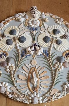 a decorative plate with shells and seashells on it's sides, sitting on a wooden floor