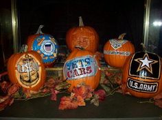 pumpkins decorated with the u s navy seal and other emblems are displayed in front of a mirror