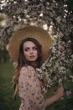 a woman wearing a straw hat and holding flowers