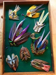 a wooden box filled with lots of different types of brooches on top of a table