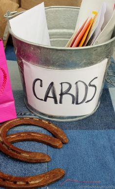 a metal bucket filled with cards next to a pink bag