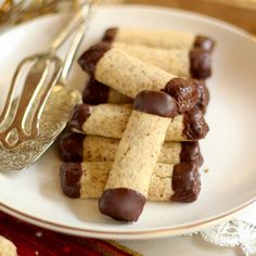 chocolate covered crackers on a white plate next to a fork and silver utensil