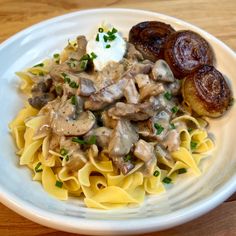 a white plate topped with pasta and mushrooms