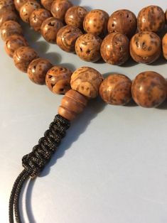 "Bodhi seed mala necklace made of 108 12mm beads with a Bodhi seed guru bead and an adjustable knot that allows you to change the length and tightness of the beads. Bodhi seeds are usually not polished so they are a solid color with small ridges or veins. Bodhi in Sanskrit translates to \"enlightened\" or \"awakened,\" therefore the Bodhi seed means \"enlightened seed.\" Bodhi is also a term in Buddhism to reflect a Buddha's understanding of the true nature of things. Many Buddhist wear the Bodh Spiritual Brown Beaded Bracelets, Spiritual Round Beaded Bracelets For Meditation, Spiritual Beaded Bracelets For Meditation, Traditional Beaded Bracelets For Meditation With 108 Beads, Adjustable Spiritual Mala For Puja, Spiritual Polished Brown Beads, Spiritual Healing Brown Beads, Spiritual Brown Polished Beads, Adjustable Traditional Mala For Healing