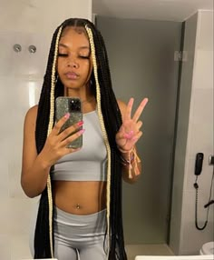 a woman with dreadlocks taking a selfie in the bathroom while holding her cell phone