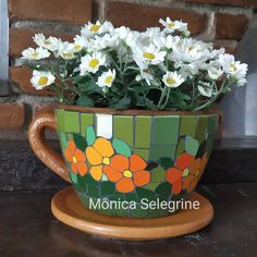 a flower pot with white flowers in it sitting on a table next to a brick wall