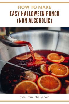 a pot filled with liquid and oranges being poured into it to make an easy halloween punch