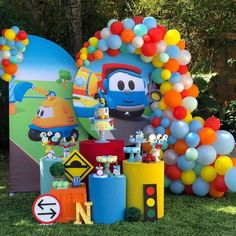 a birthday party with balloons and decorations on the grass in front of a train theme