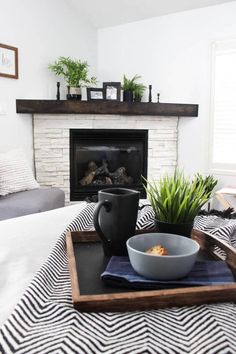 a living room with a fire place and a tray on the bed