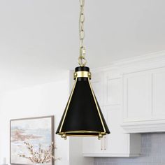 a black and gold pendant light hanging from a kitchen ceiling over a white countertop