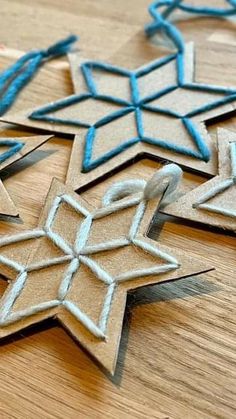 some very pretty little ornaments on a wooden table with blue string and thread around them