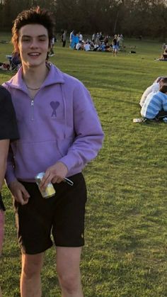 two young men standing next to each other on a field with people in the background