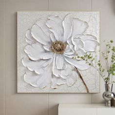 a large white flower is hanging on the wall above a dresser in a room with beige walls