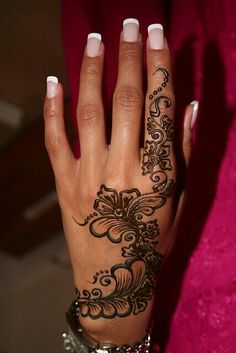 a woman's hand with black and white henna tattoos on her left hand