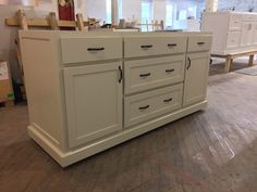 an unfinished kitchen island in the middle of a room with white cabinets and wood floors