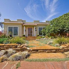 a house that is in the middle of some grass and bushes on the front lawn