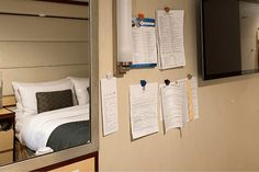 a hotel room with several pieces of paper taped to the wall next to a bed