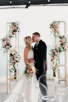 a bride and groom kissing under an arch decorated with flowers