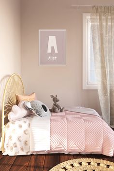 a small child's bedroom with pink walls and wood flooring, including a wicker bed