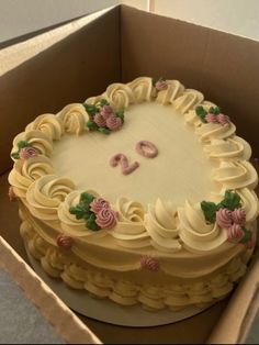 a birthday cake in a box with the letter d on it's side and flowers around the edges